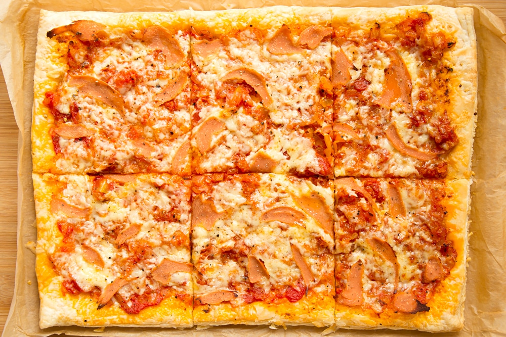 Overhead shot of sliced puff pastry pizza in a baking tray