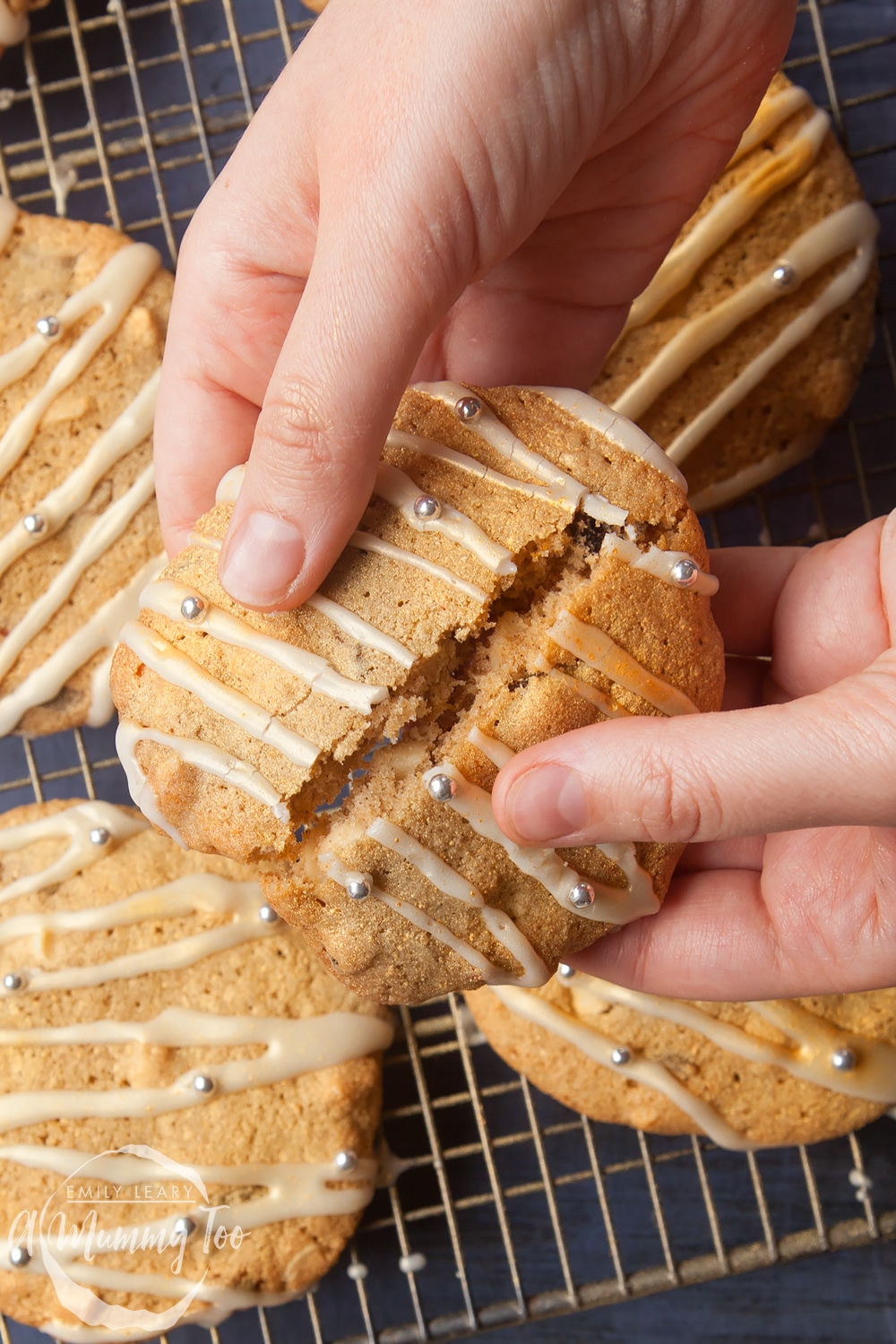 Overhead shot of a hand breaking a white chocolate cookie in half