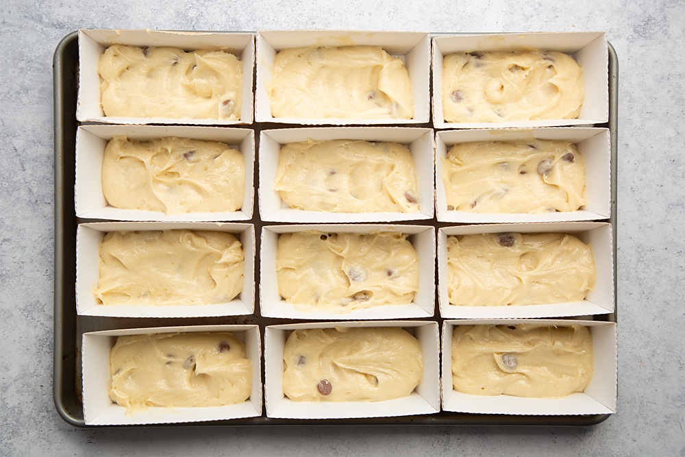 Overhead shot of the chocolate chip mini-loaf cake with chocolate frosting mixture being added to the trays.