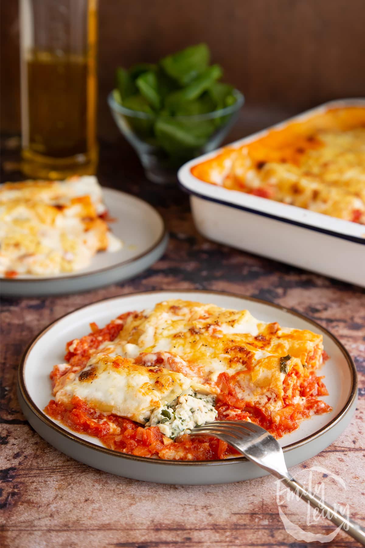 A fork cutting open the Spinach and ricotta cannelloni on a plate.