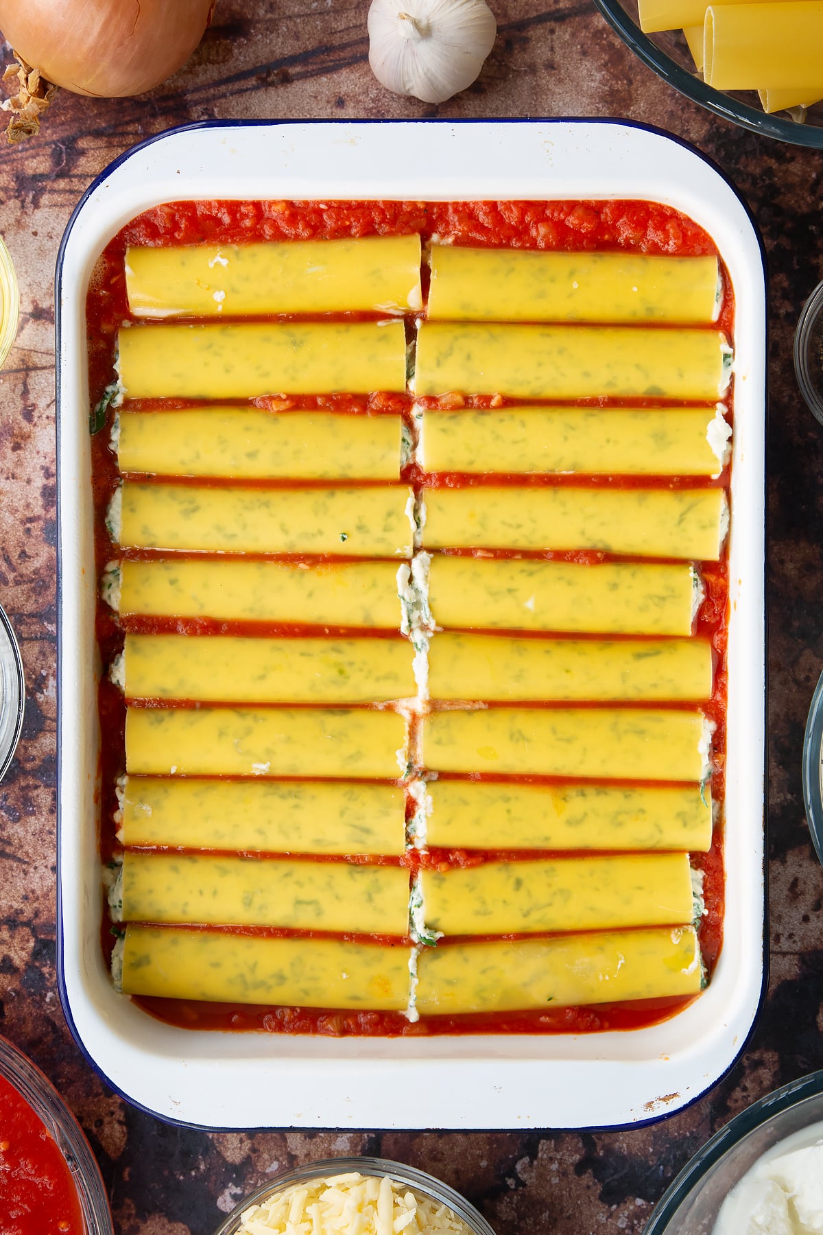 Overhead shot of the spinach and ricotta cannelloni ontop of the tomato base in a baking dish.
