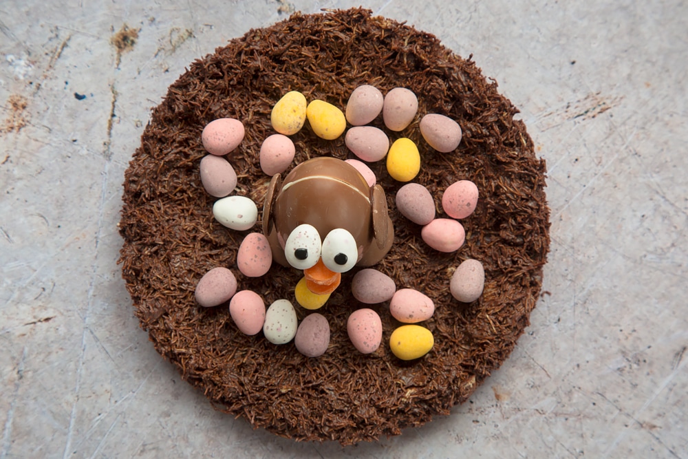 Chocolate Easter egg chick surrounded by mini eggs in a chocolate shredded wheat nest