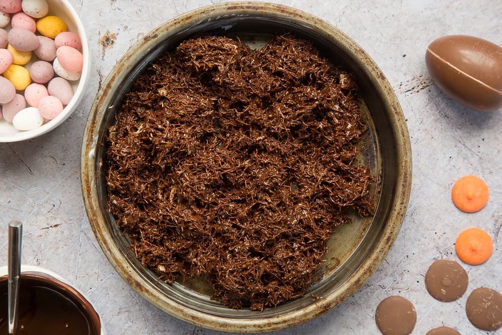 Shredded wheat covered in melted chocolate, shown inside a greased sandwich tin