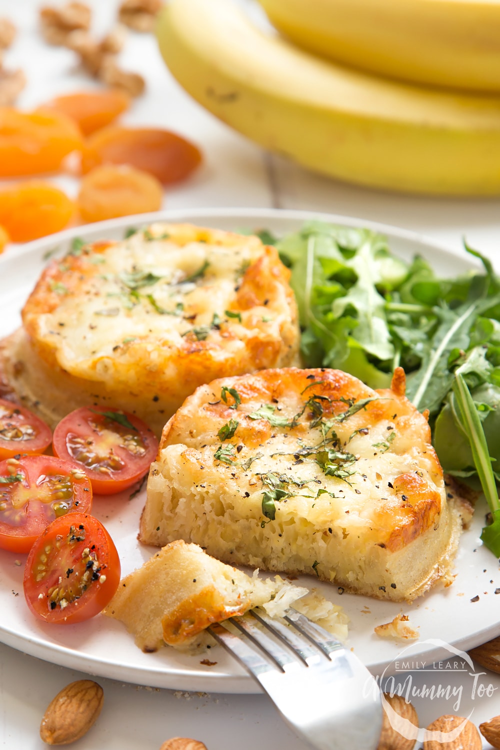 Two Baked eggy crumpets on a white plate with a salad on the side.