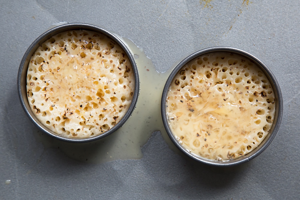 Overhead shot of the two crumpets inside the egg rings having been covered in the whisked milk and egg.