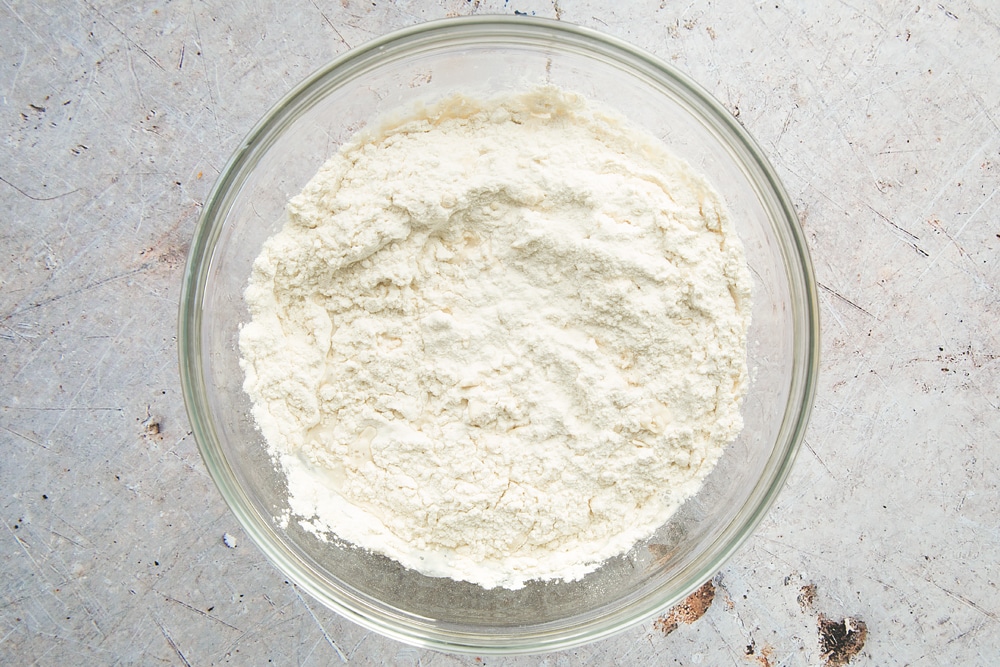 Warm water mixture topped with flour in a large clear bowl