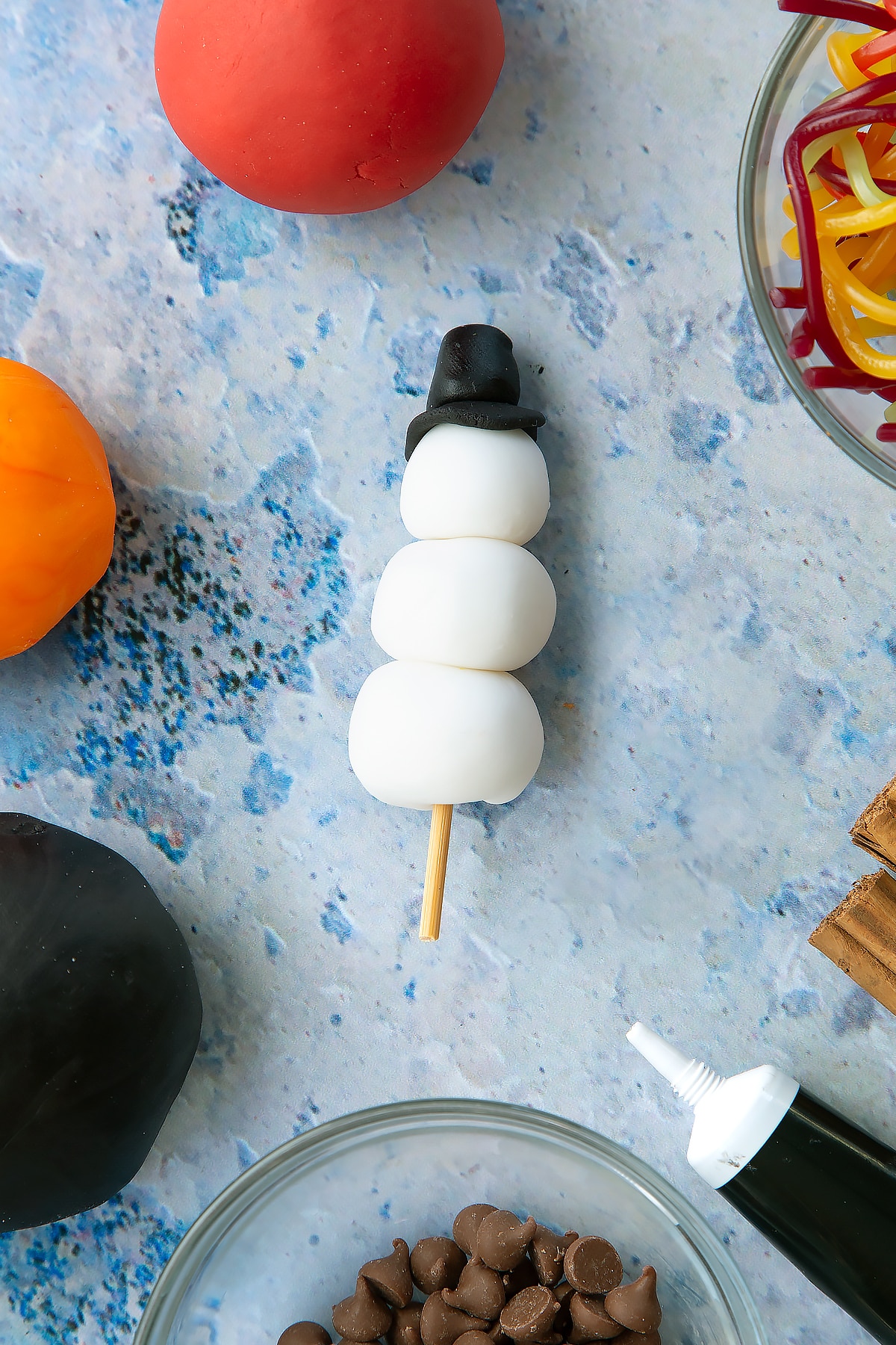 The snowman having been put together on a skewer. Ready to be added to the cupcake.