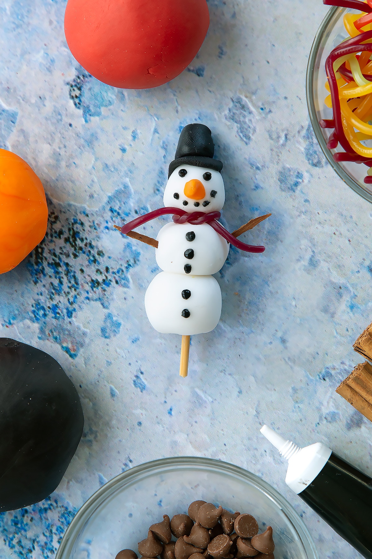 Adding a strawberry lace to the sugar paste snowman to demonstrate the scarf.