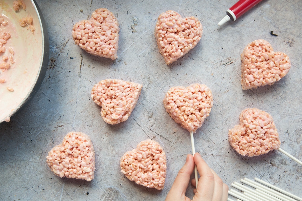 Pushing the stick into the heart crispy cake pops mix.