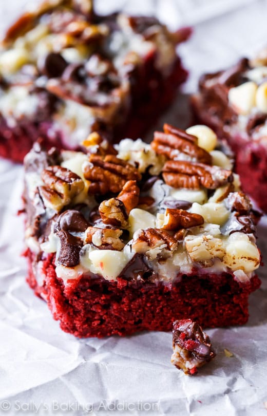 slices of Red Velvet Seven Layer Bars on a greaseproof paper base.