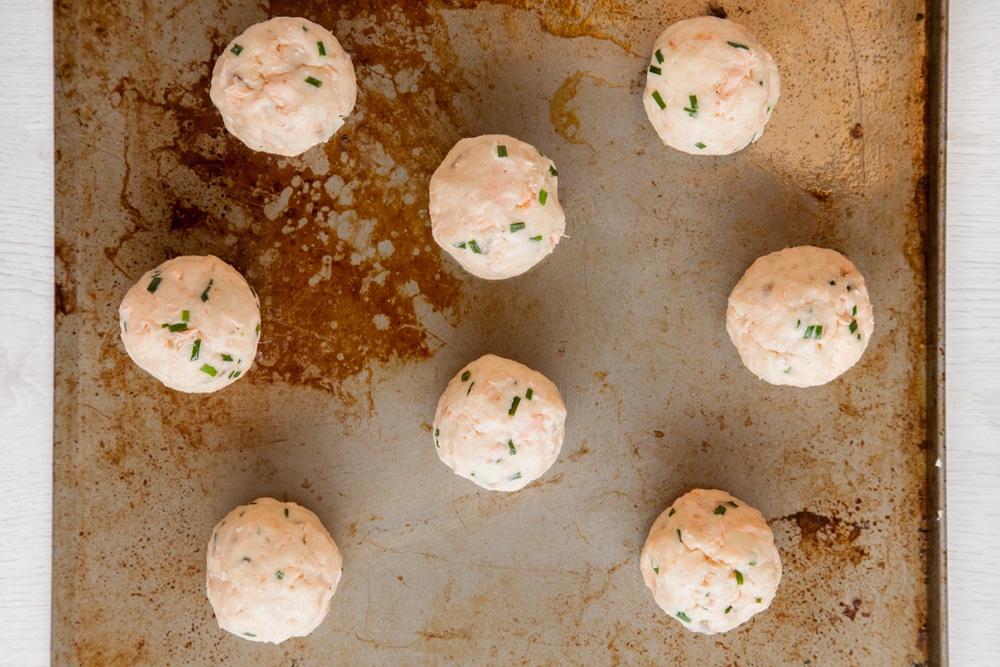 Baked fish cakes without breadcrumbs mixture rolled into balls and laid out on a baking sheet.