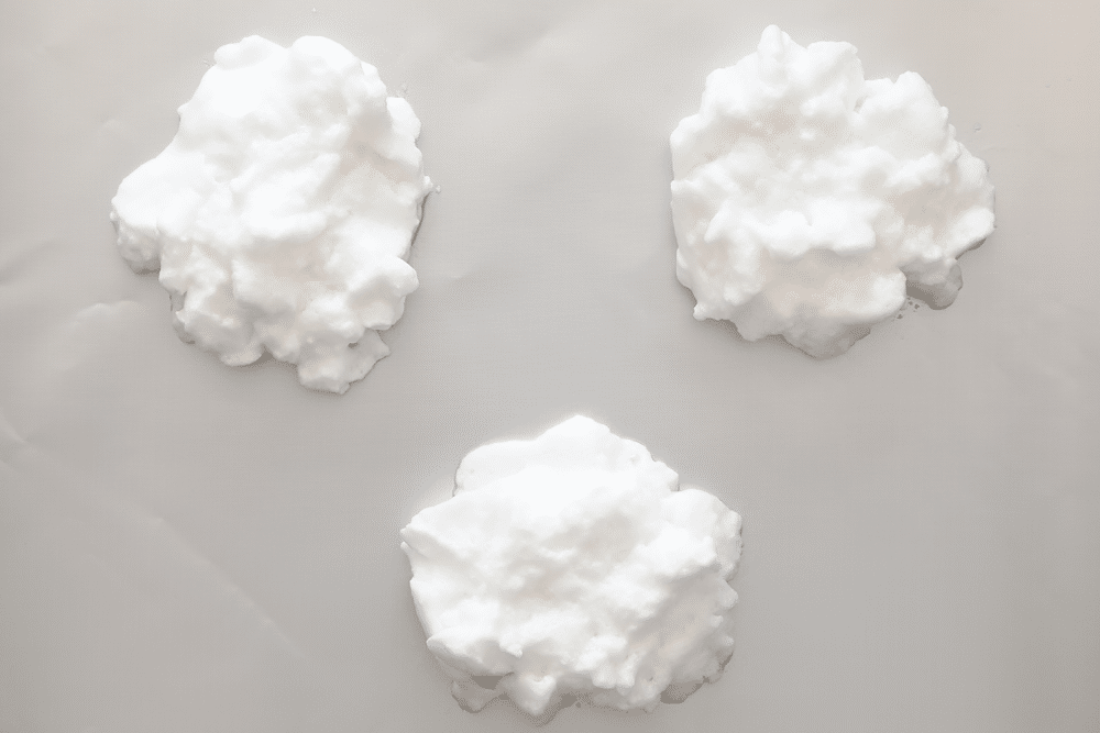 Egg clouds using whipped egg whites, in three piles on a baking sheet.
