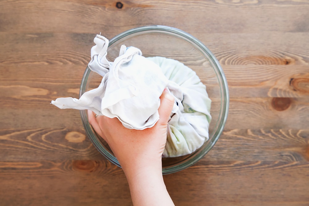Using a clean cloth to drain the liquid from the vegetables