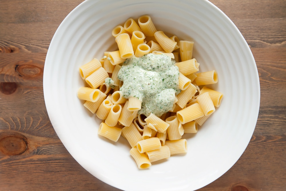 Topping the rigatoni with freshly made pesto