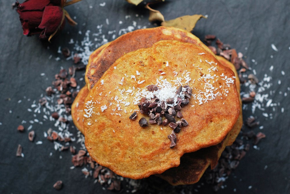 butternut squash and carrot pancakes by rough measures stacked on a slate board with a sprinkle of coconut.