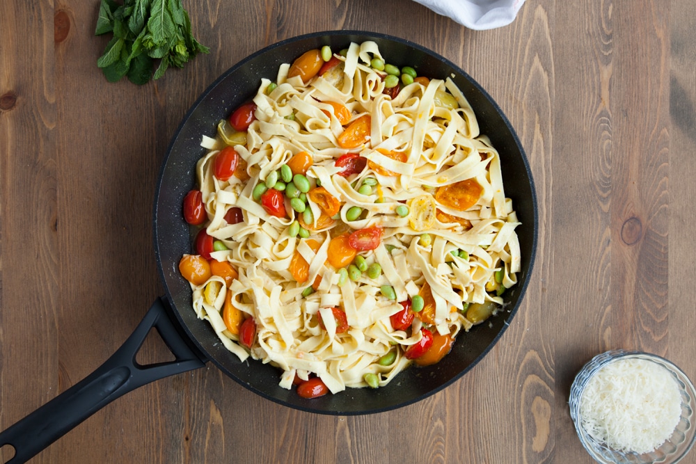 Heating the tagliatelle with tricolour tomatoes, edamame and mint until the sauce becomes creamy