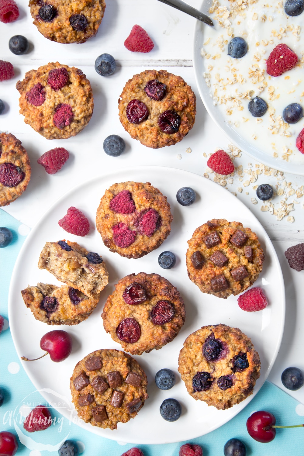 Yoghurty summer fruit breakfast muffins surrounded by raspberries, blueberries and yoghurt. Find out how to make this delicious, healthier breakfast treat in my recipe!