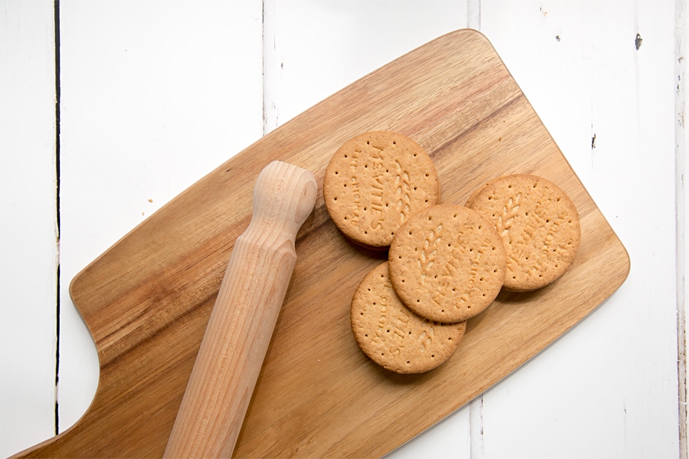 Preparing the digestive biscuits for the cheesecake base ona wooden chopping board and rolling pin