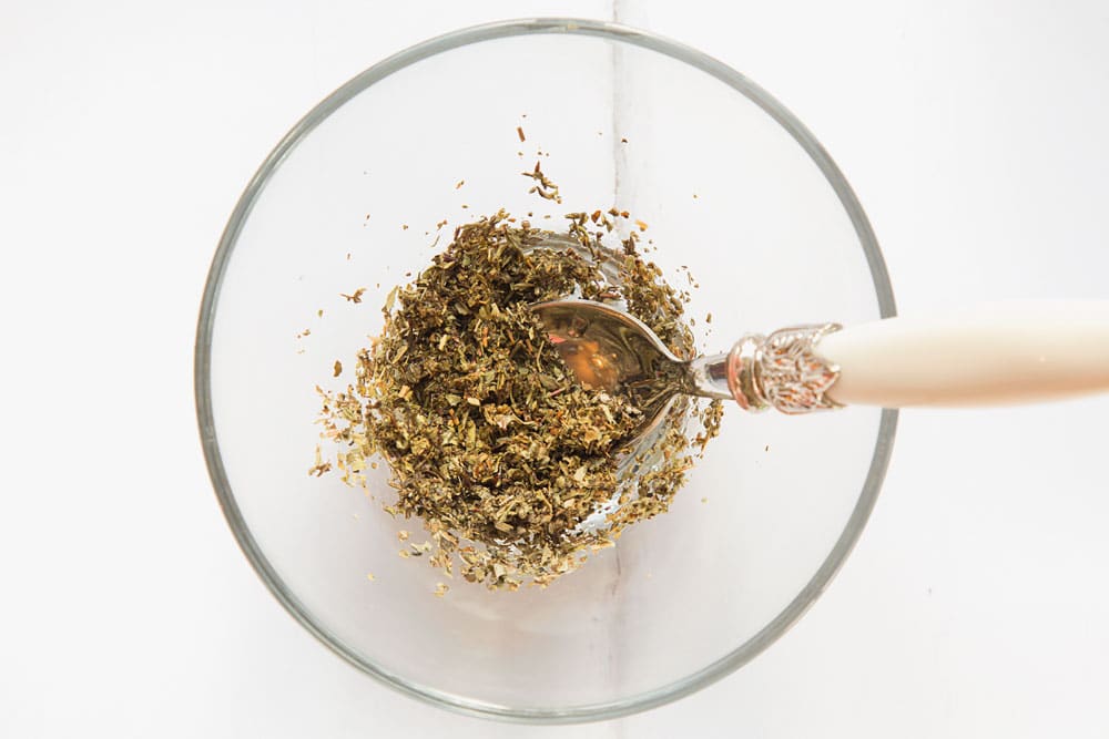 Thyme, oregano and sage are mixed in a bowl