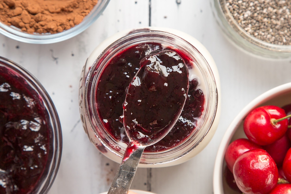 Cherry conserve is layered on top of the breakfast jar