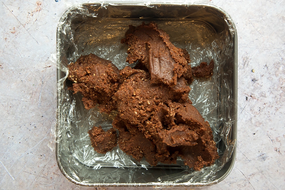 The healthier chocolate bars mixture is tipped into a baking tray lined with cling film