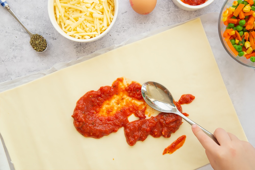 Spreading tomato puree on the unrolled pastry