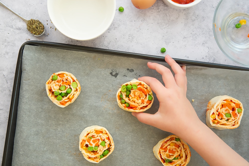 Veggie pizza roll-ups on a baking tray, ready to be baked in the oven