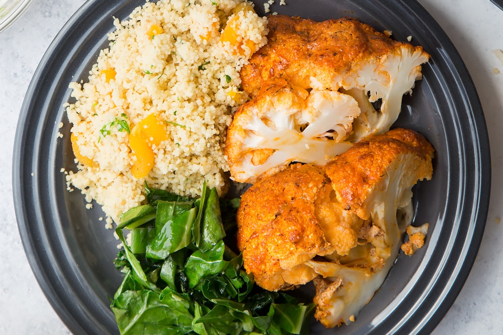 Harissa roasted cauliflower served with spring greens and herby couscous
