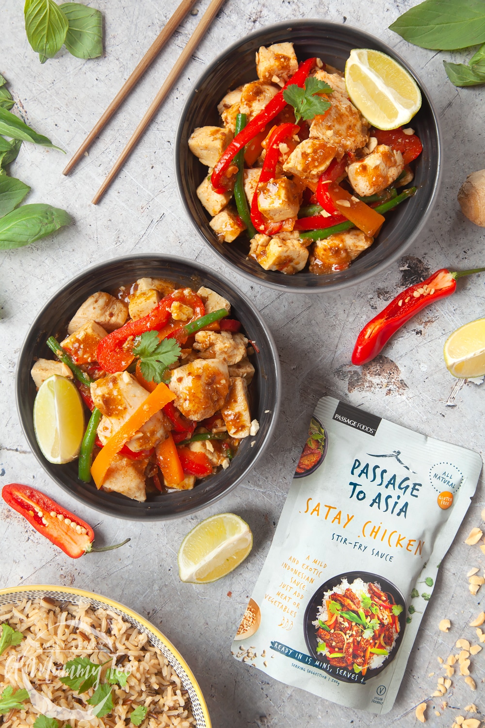 Chicken and tofu satay stir-fry made with Passage to Asia sauce served in a black bowl with chopsticks on the side.