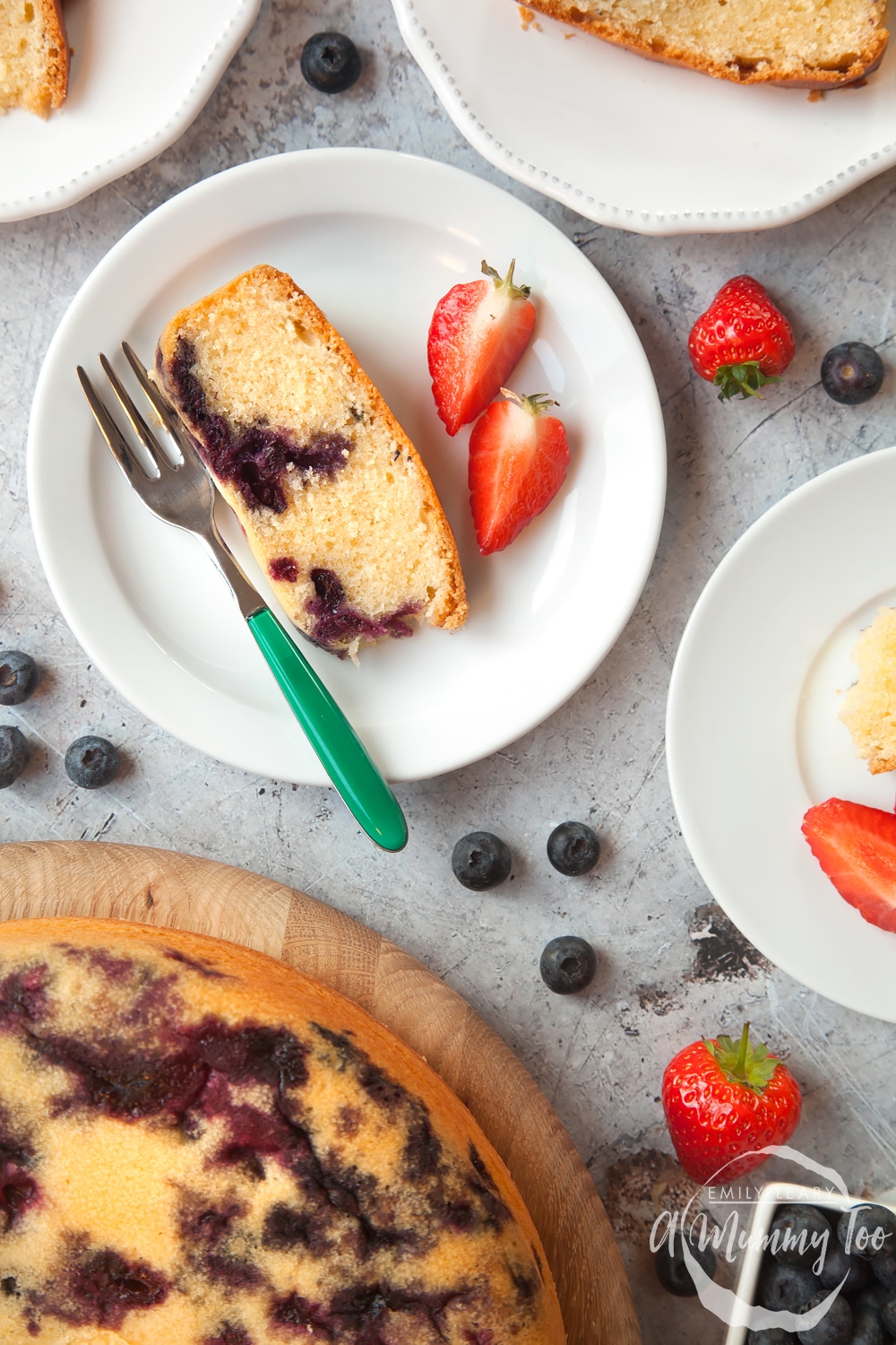 Blueberry cake cut into slices and served with sliced strawberries
