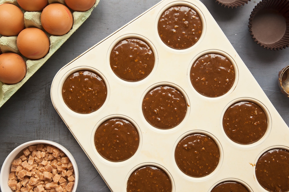 Overhead shot of muffin tray with mixture in a large clear bowl