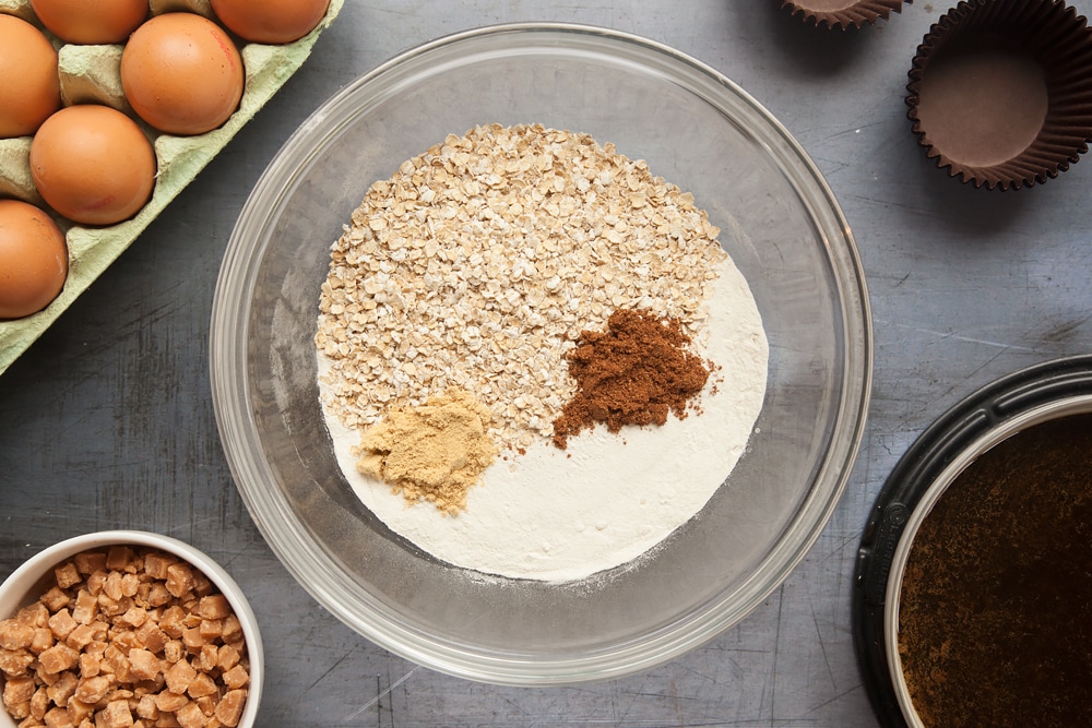 Overhead shot of flour, oats, ginger and mixed spice in a large clear bowl