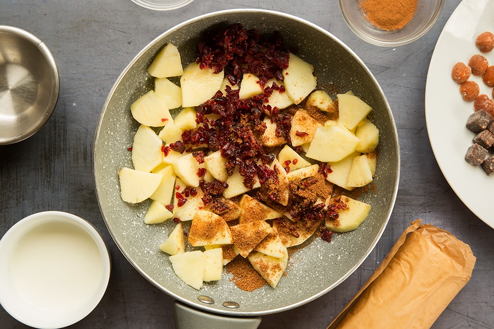 Chopped apple, cranberries and mixed spice in a frying pan