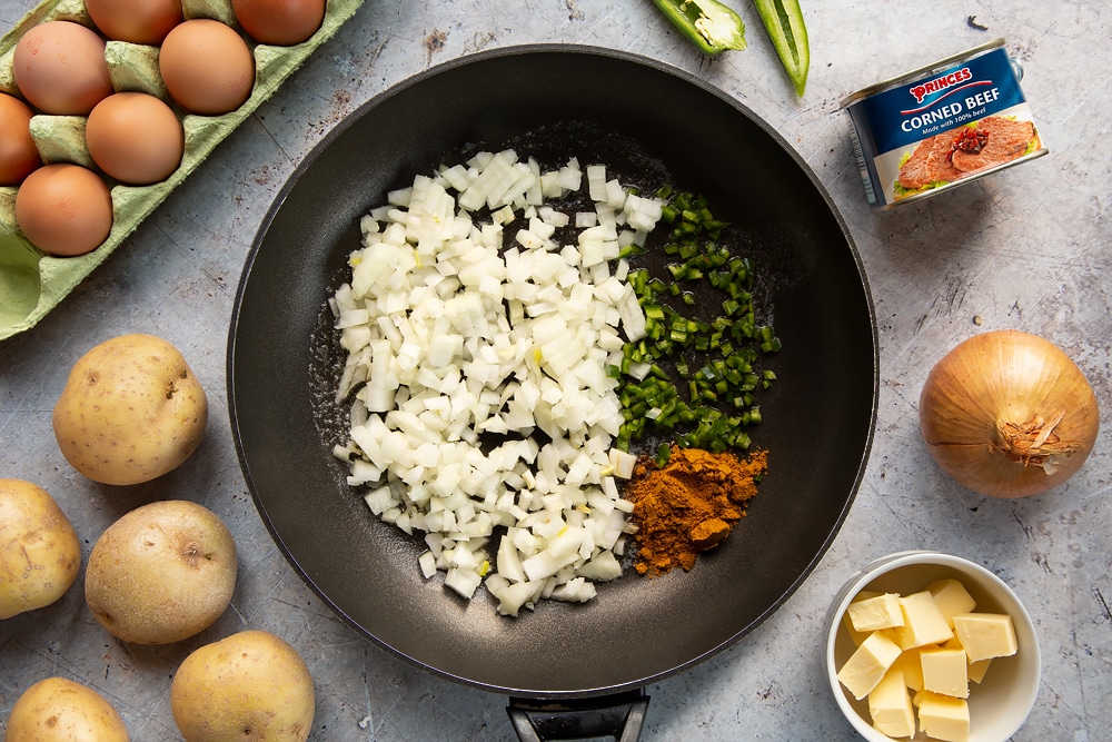 Chopped onions, curry powder and green chilli in a frying pan