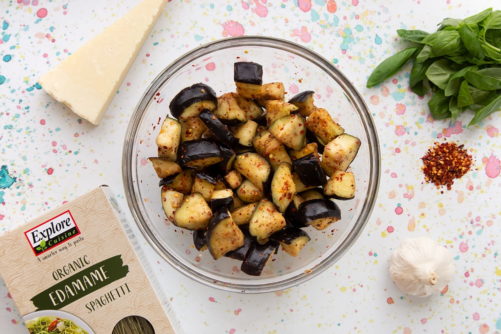 A bowl of chopped aubergine chunks with chilli flakes on top to be used in our spaghetti alla norma recipe.