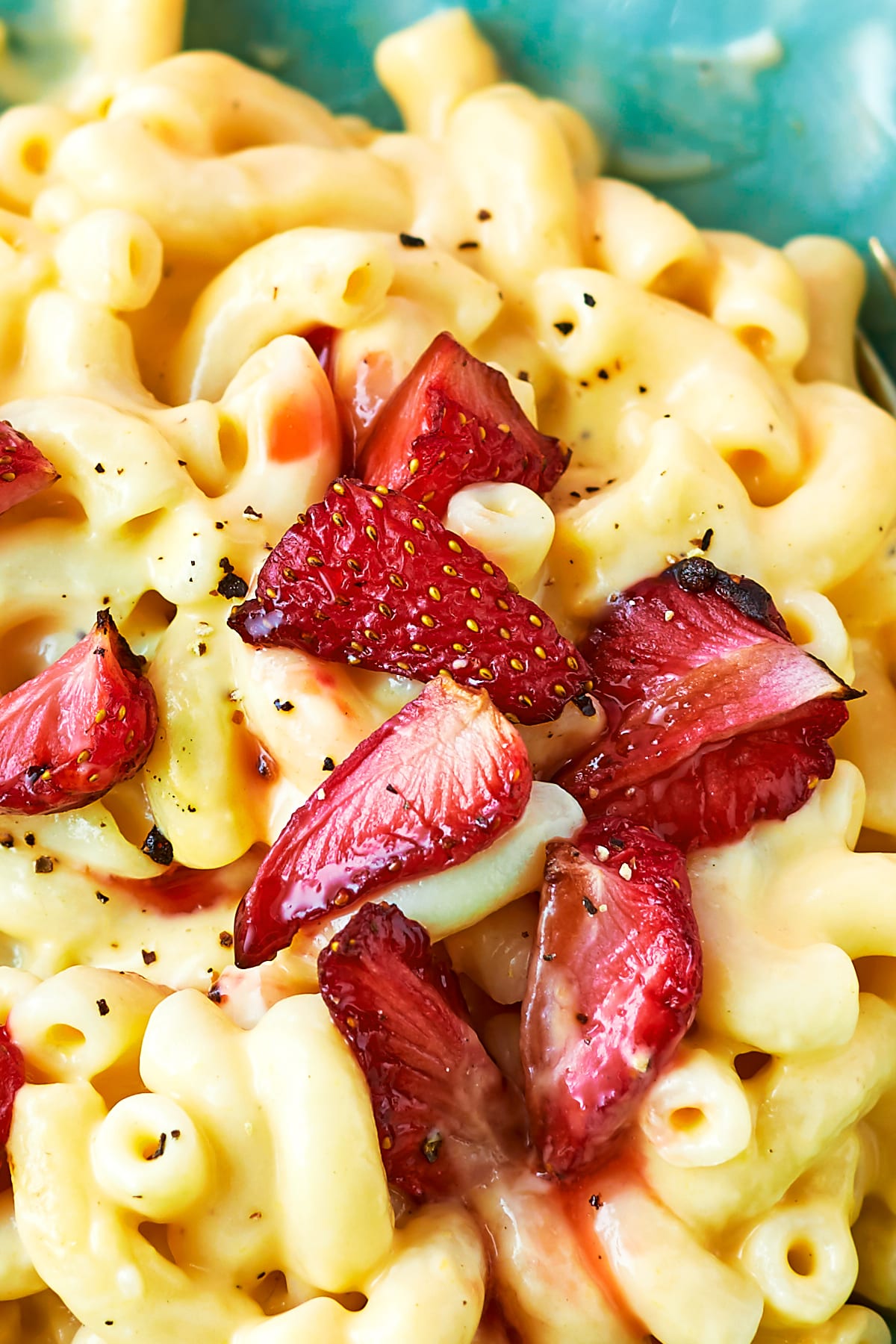 Close up of a bowl of strawberry pasta: macaroni in a cheese and butternut squash sauce, topped with roasted balsamic strawberries.