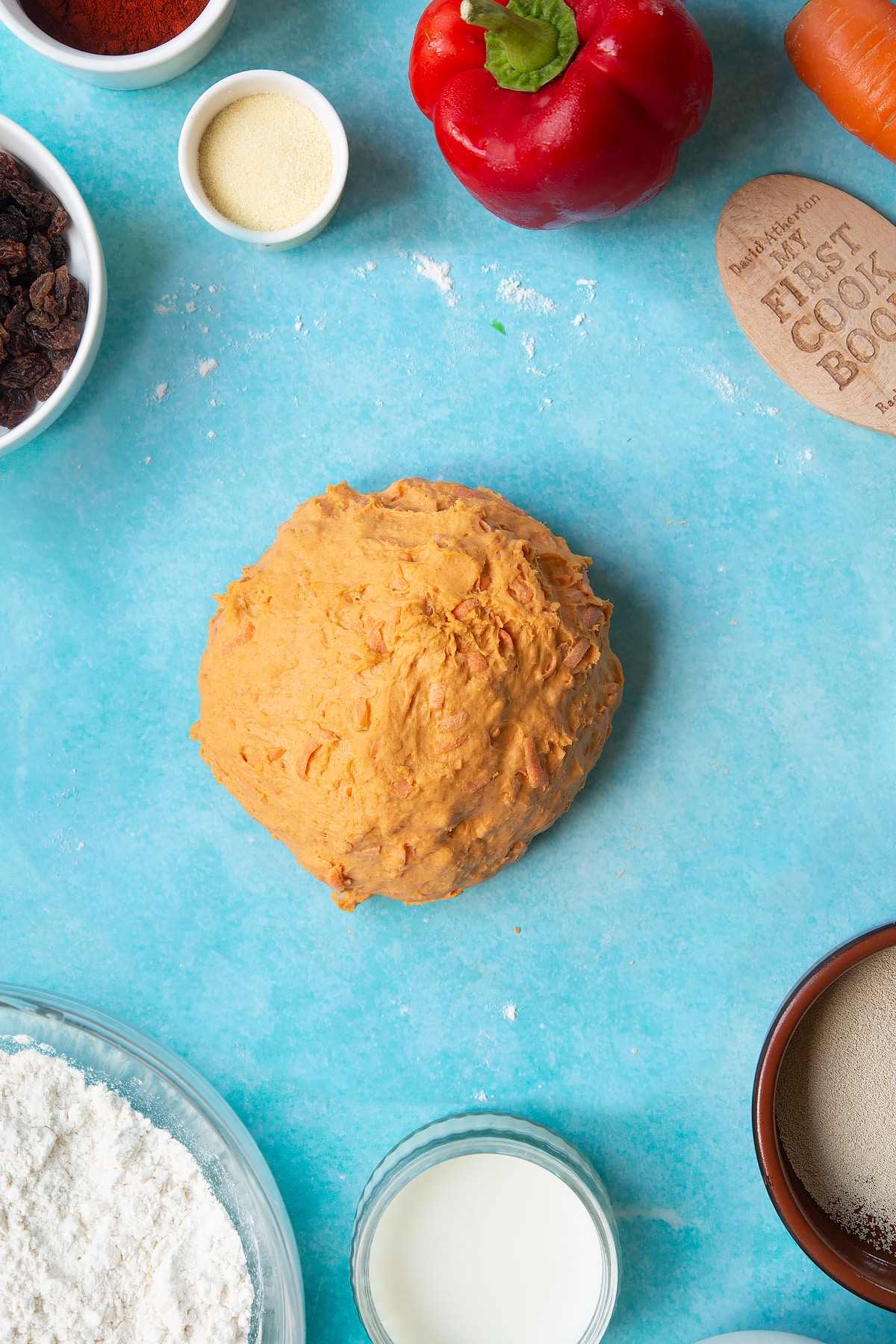 Paprika and carrot bread dough, freshly kneaded. Ingredient to make bread snakes surround the dough.