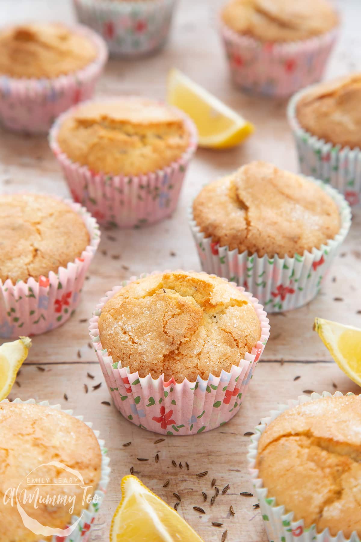 Front angle shot of caraway seed muffin with lemons in the side and a mummy too logo in the lower-left corner