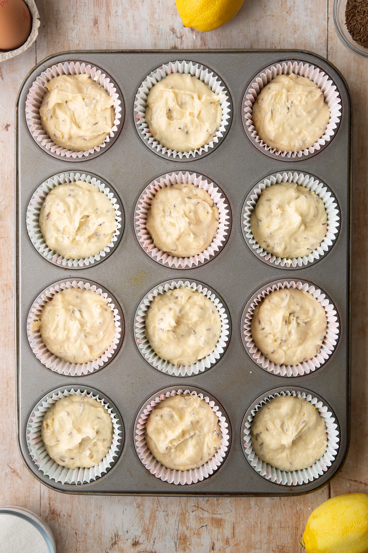 Overhead shot of muffin mix in a 12 hole muffin tray lined with paper cases