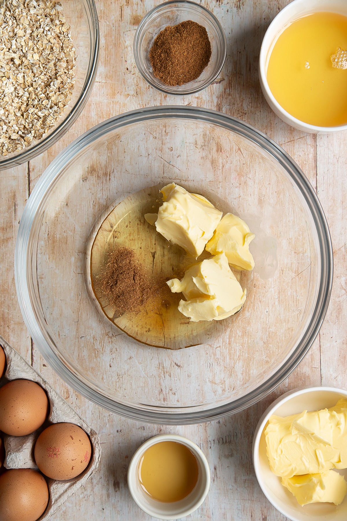 Overhead shot of margarine, vanilla, spice and syrup in a microwave-safe mixing bowl