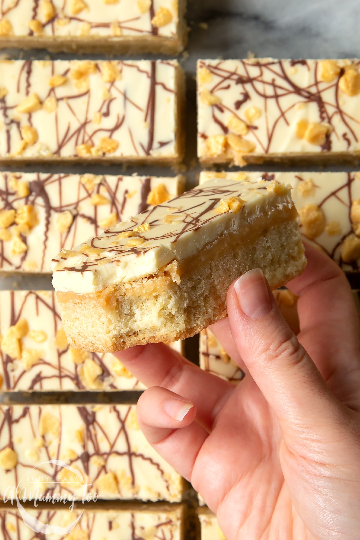 Overhead shot of a hand holding a shortbread with a mummy too logo in the lower-left corner
