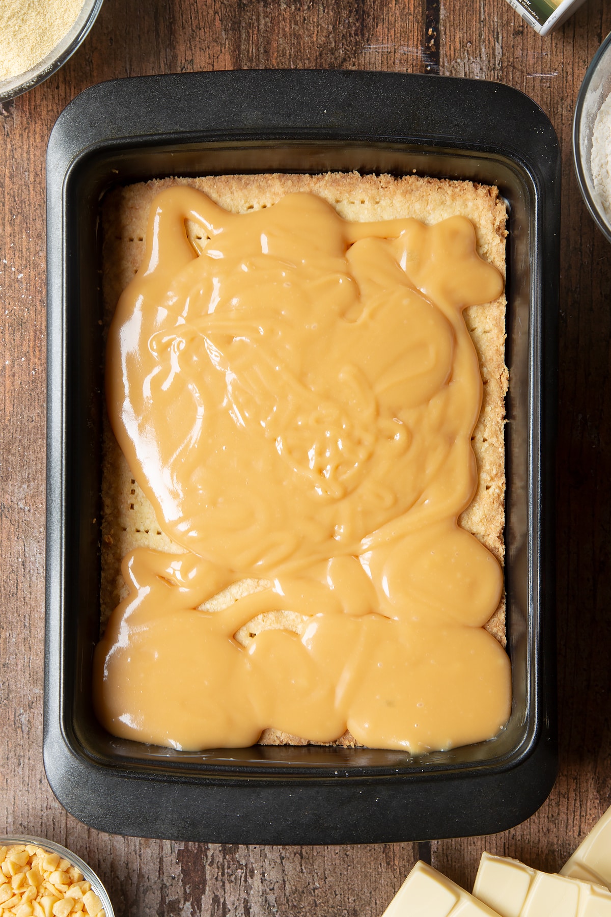 Pouring the caramel ontop the cool biscuit covering.
