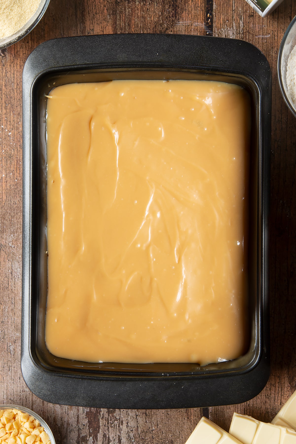 Overhead shot of the caramel being spread to the edges of the cake tin.
