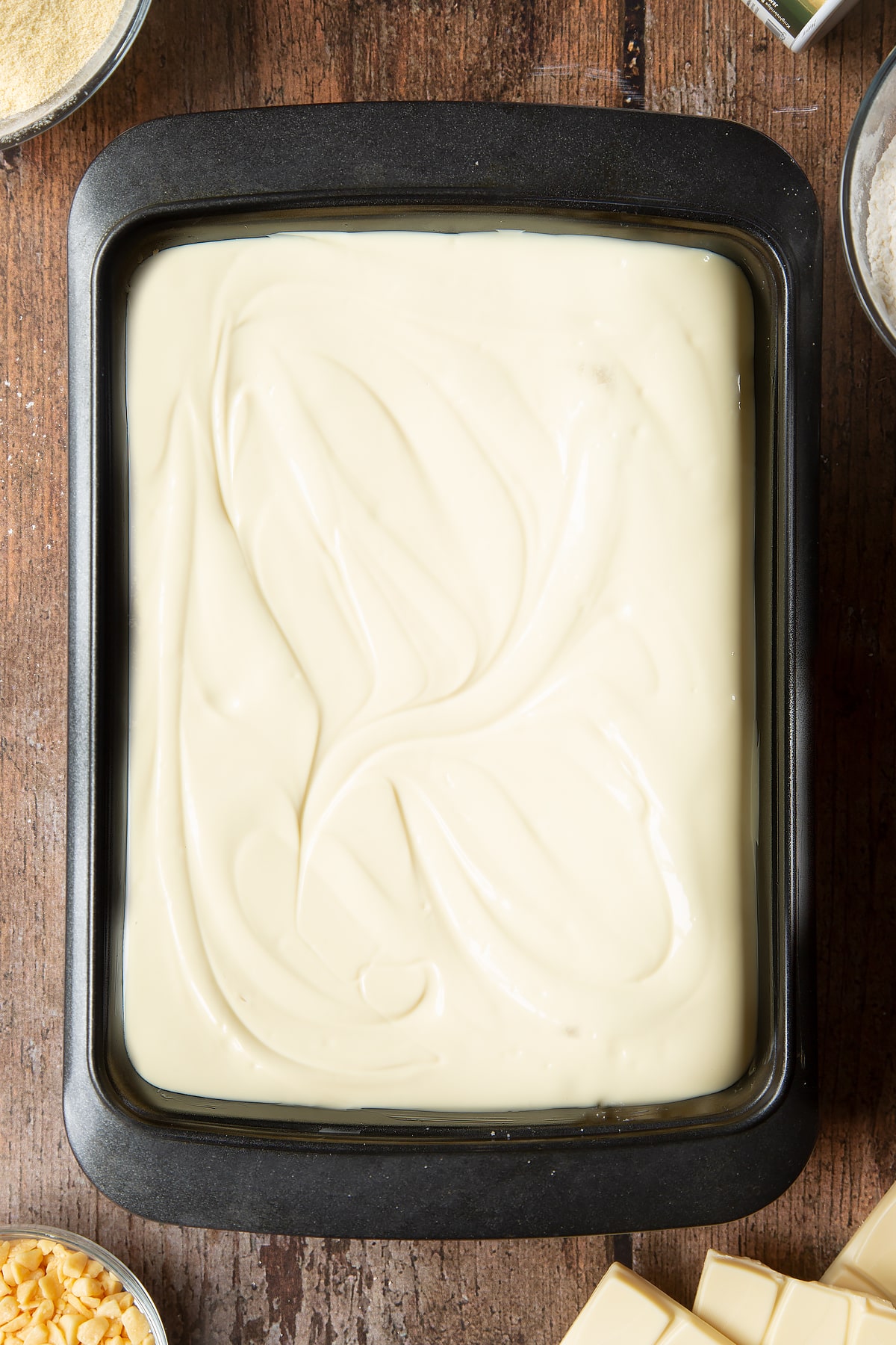 Overhead shot of the whte chocolate being poured over the caramel inside the cake tin.
