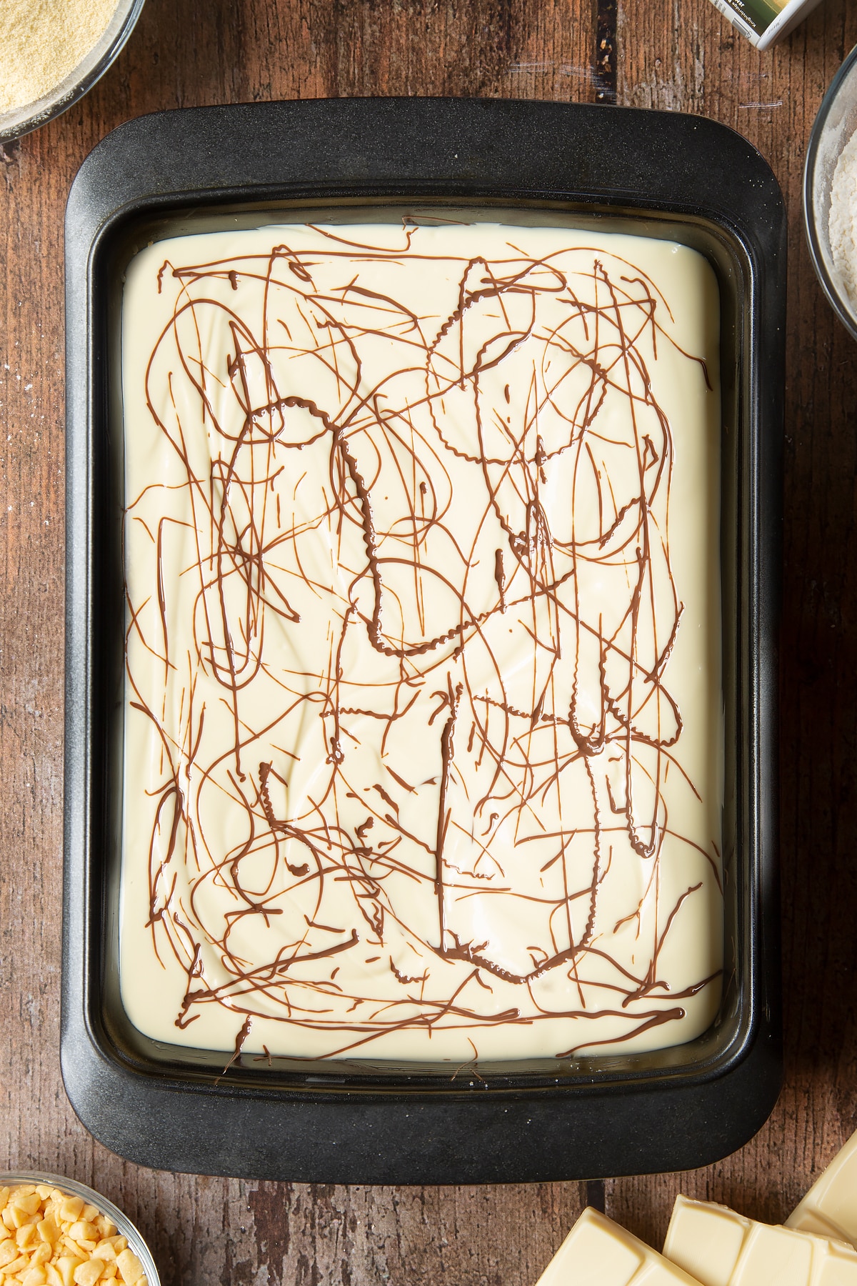 Ovehread shot of the milk chocolate drizzled over the top of the white chocolate inside the cake tin.