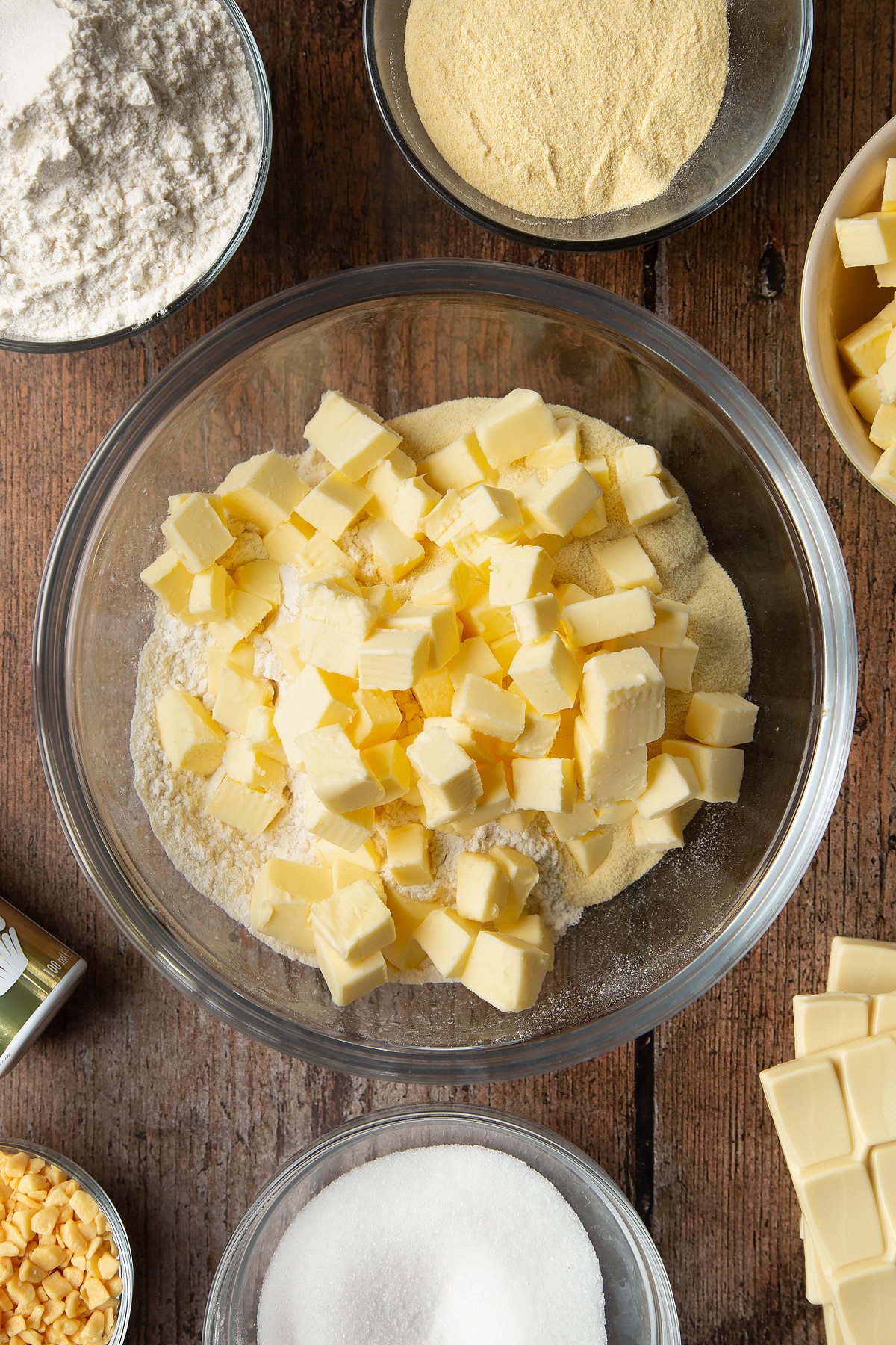 Overhead shot of cold, cubed butter and dry ingredients in a large clear bowl