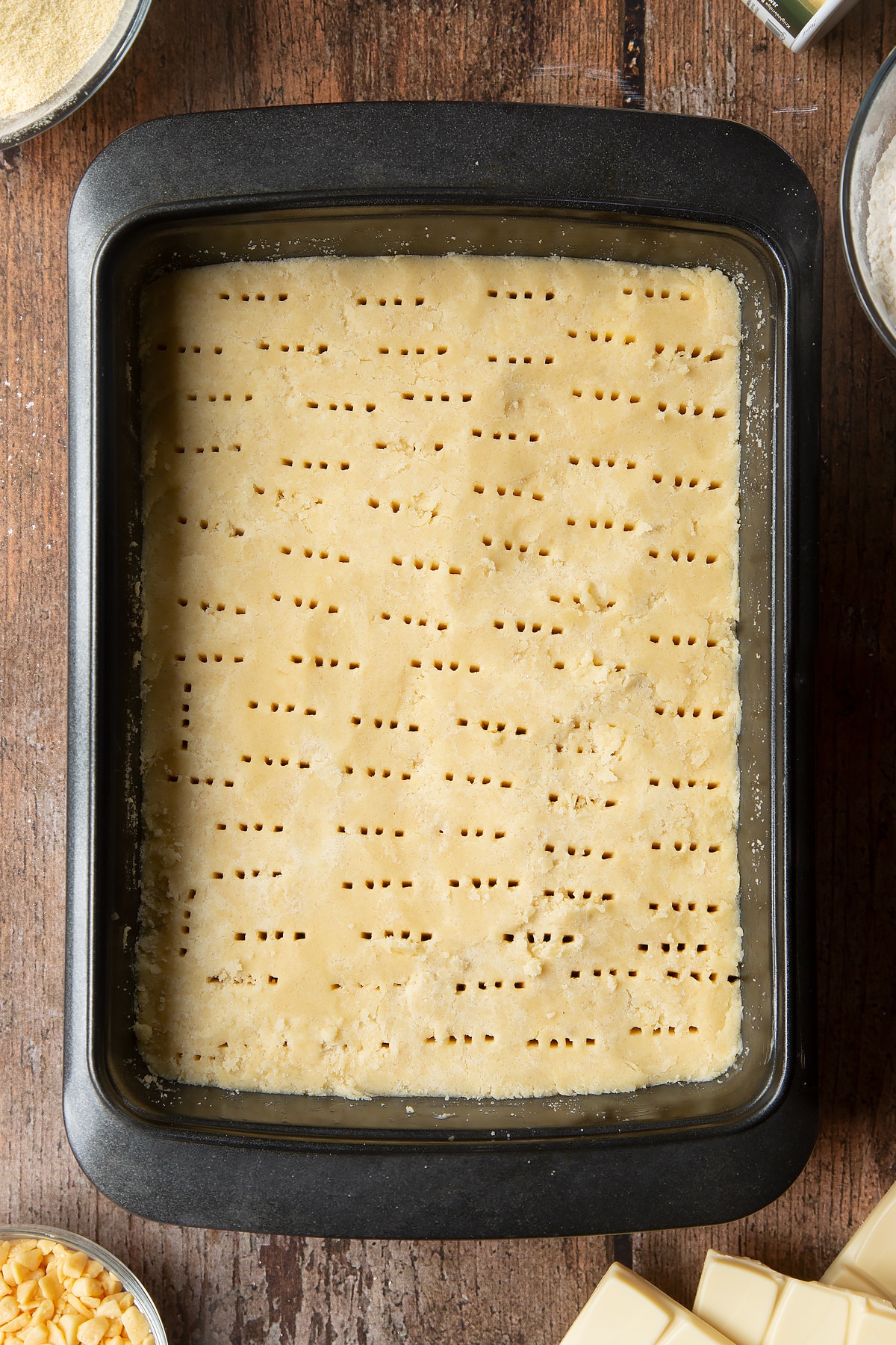 Overhead shot of dough with fork holes in a medium roasting tin