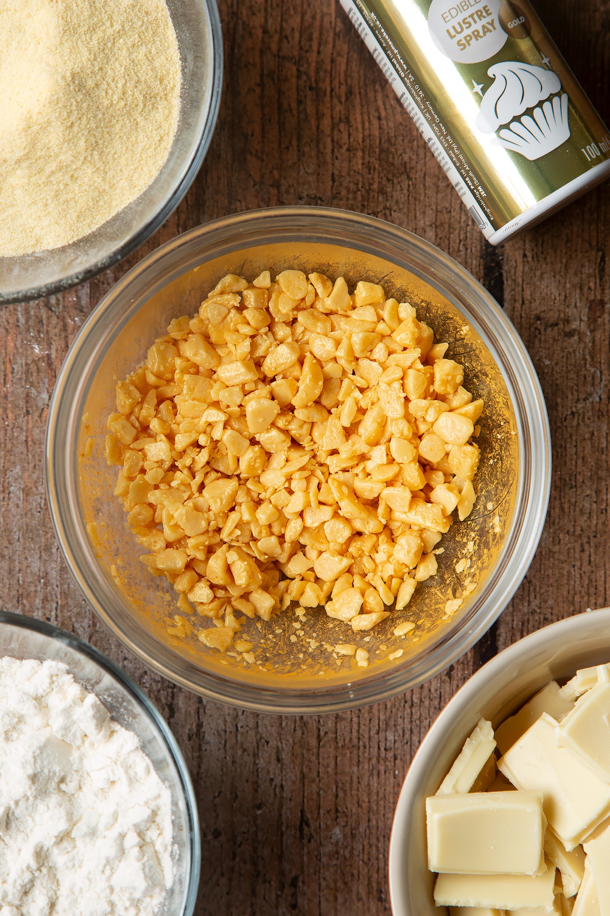 Adding edible golden spray ontop of the honeycomb pieces in a clear bowl.
