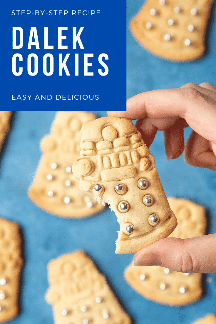 Hand holding a Dalek cookie decorated with silver candy balls on a blue background. It has a bite out of it. Caption reads: step-by-step recipe Dalek cookies easy and delicious.