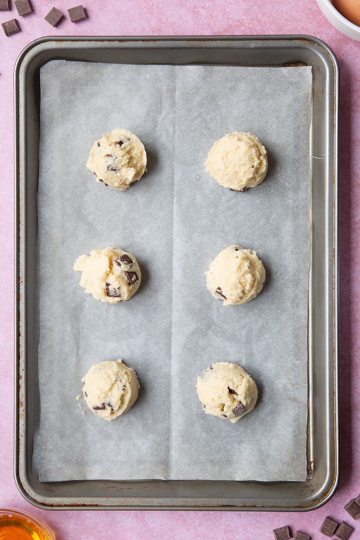 Overhead shot of chewy dark chocolate chip cookies dough on a baking tray